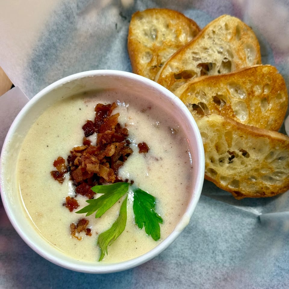 Creamy soup topped with bacon bits and parsley, served with toasted bread slices.